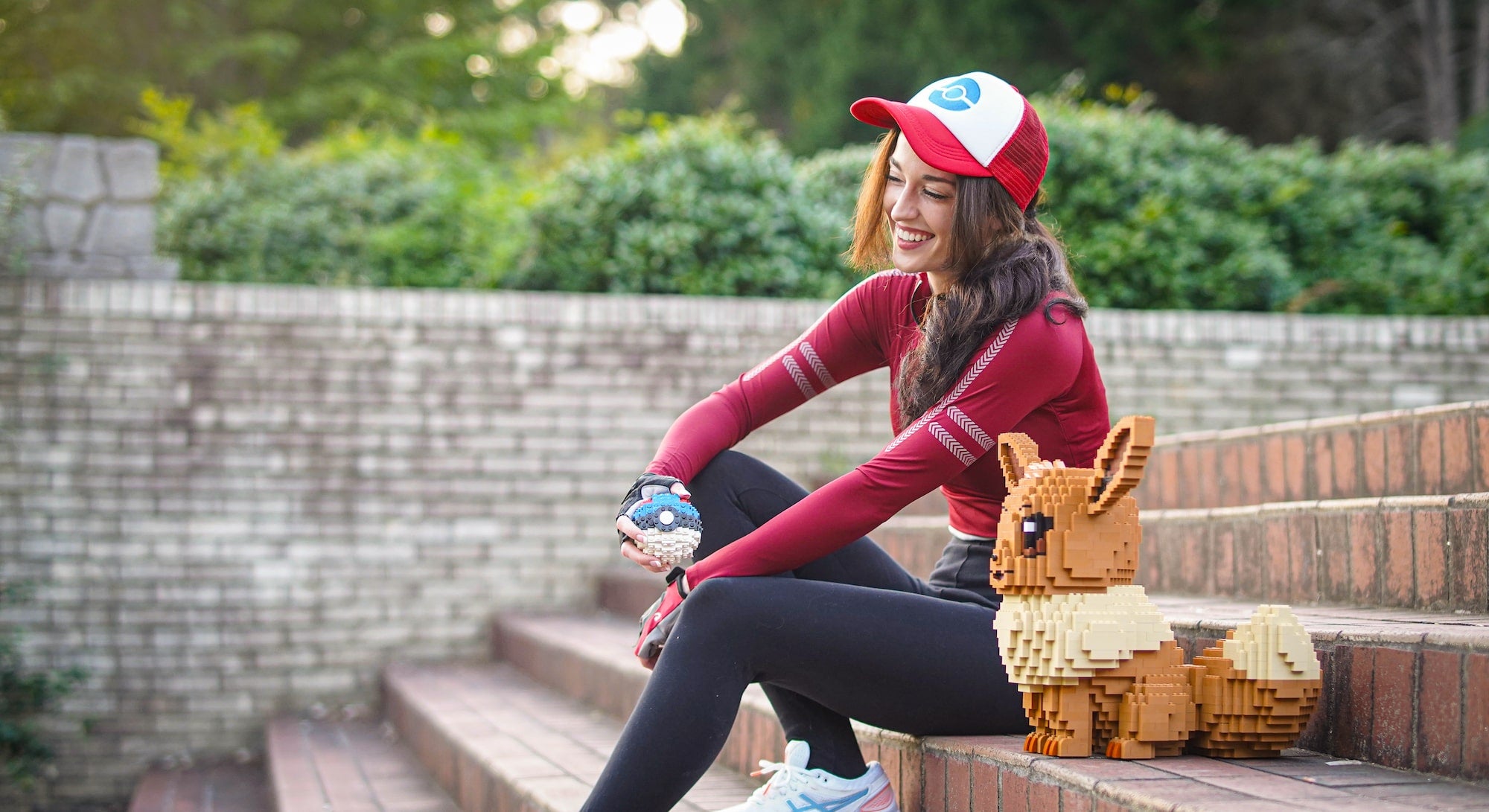 woman sitting on steps next to eevee bricker builds lego build and holding poke ball bricker builds lego build